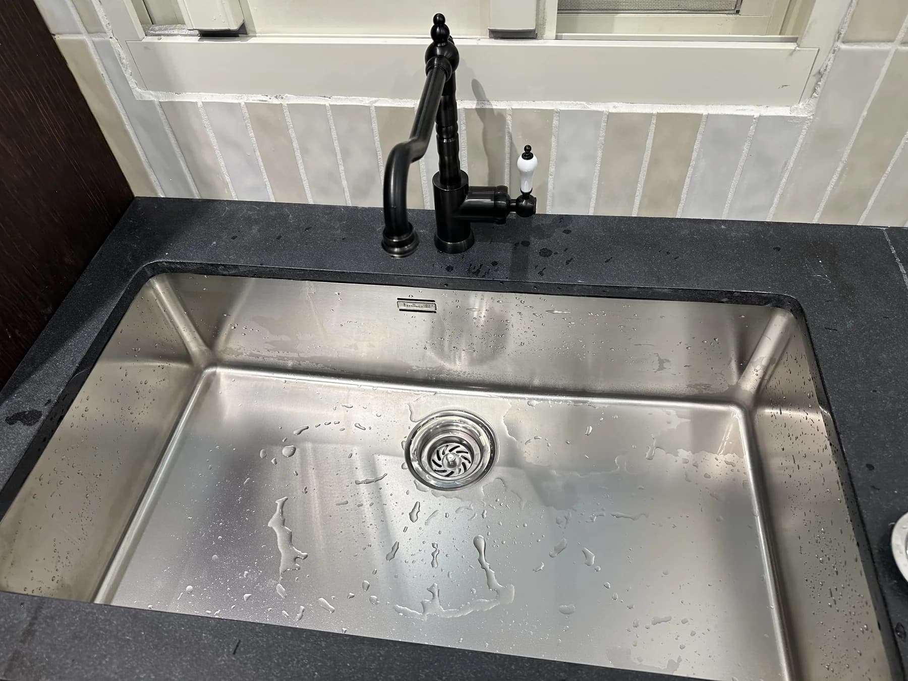 黑色檯面、不鏽鋼水槽與黑色水龍頭配置