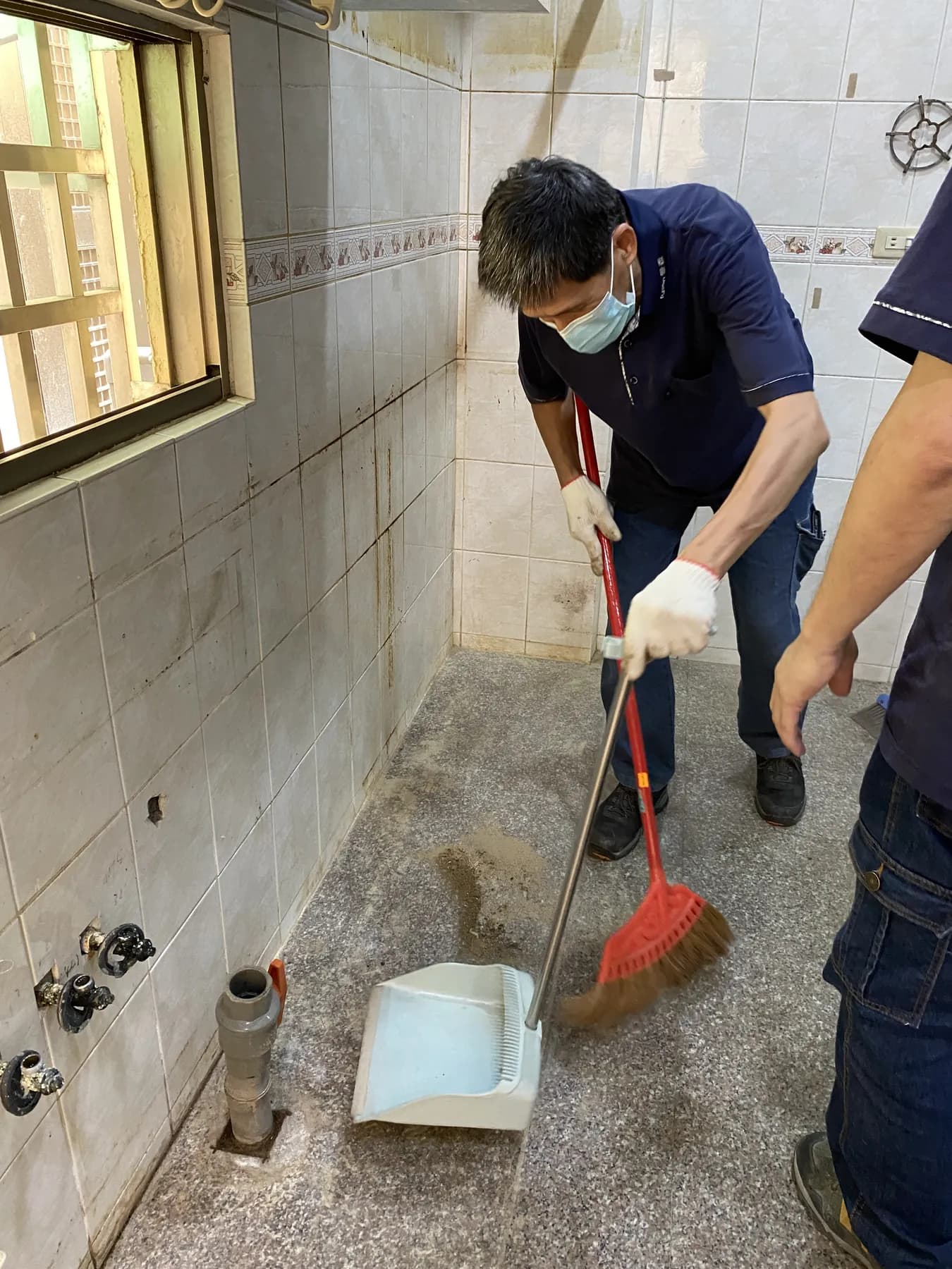 施工人員清理舊櫃拆除後的磁磚地面與牆角