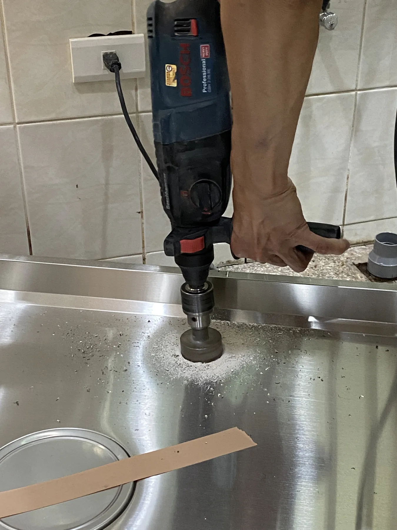 施工人員使用工具在不鏽鋼水槽檯面進行圓孔加工