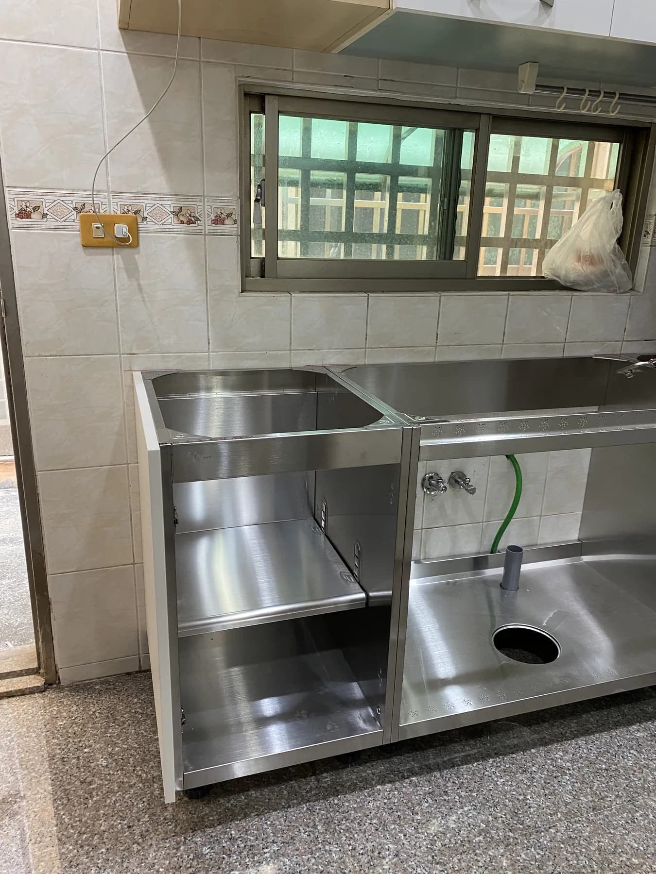 窗下完成定位的不鏽鋼檯面、水槽與水龍頭預留孔
