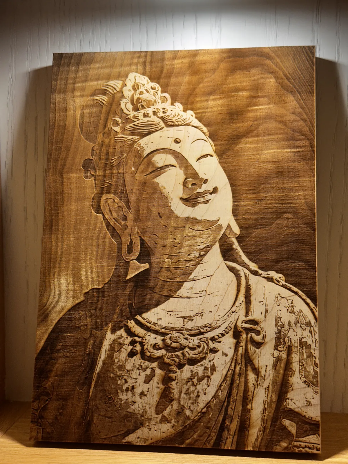 佛像側臉與衣飾細節雕刻在木板上的作品