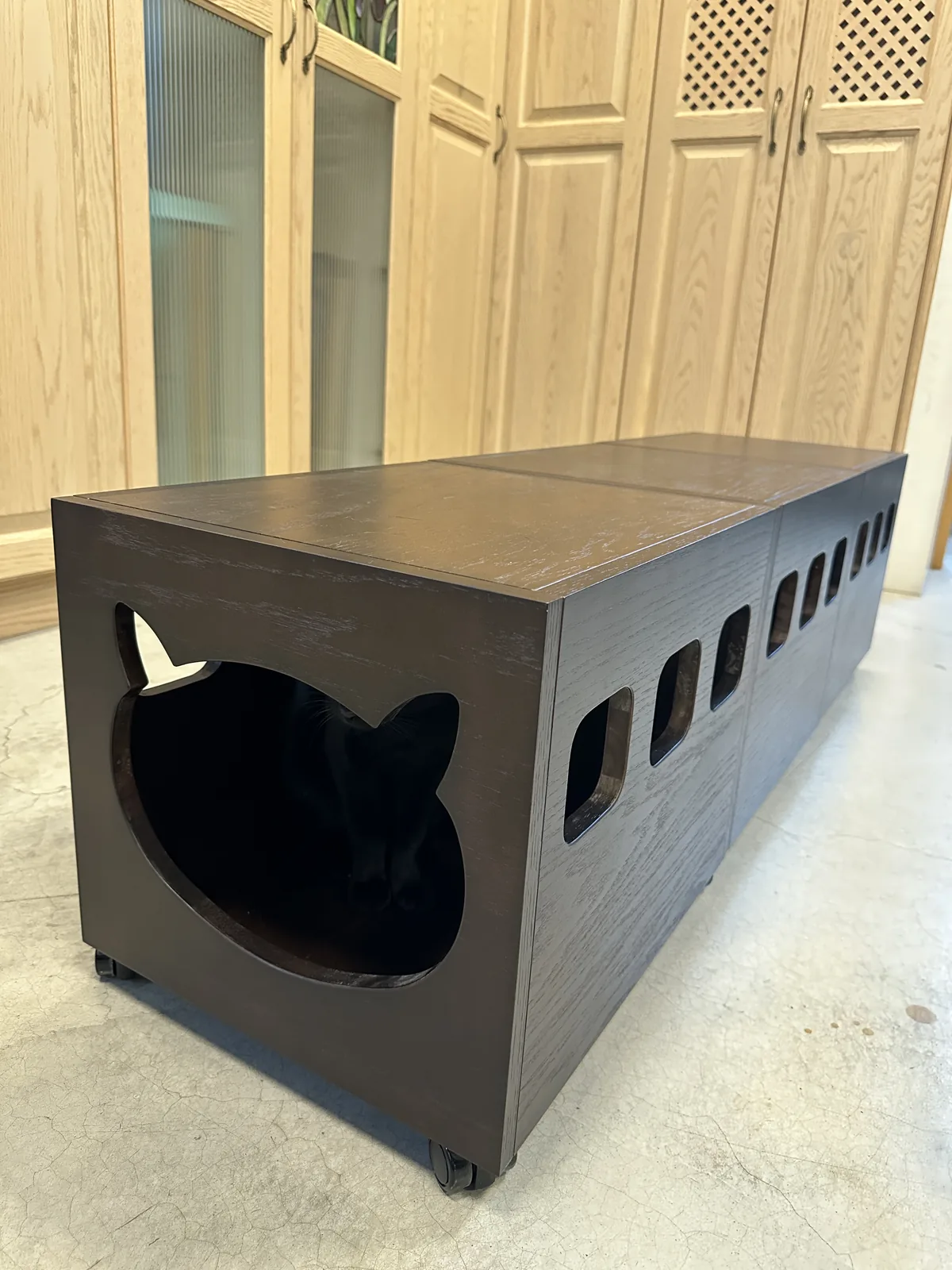 深色家具式木作貓屋的側面開孔與腳輪