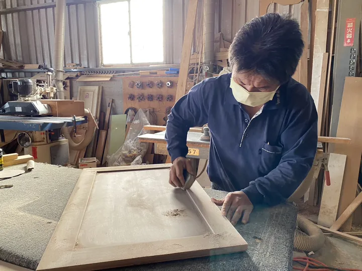 師傅在工作台上手工研磨框板門表面