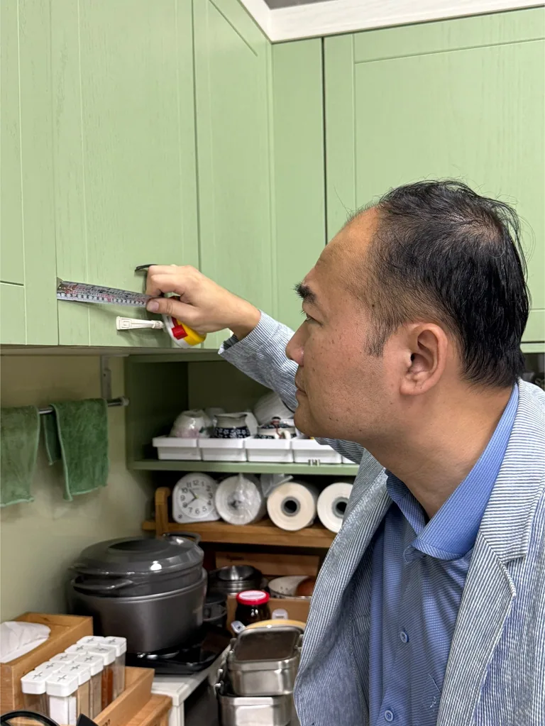 森老闆以捲尺量測廚房門板間距