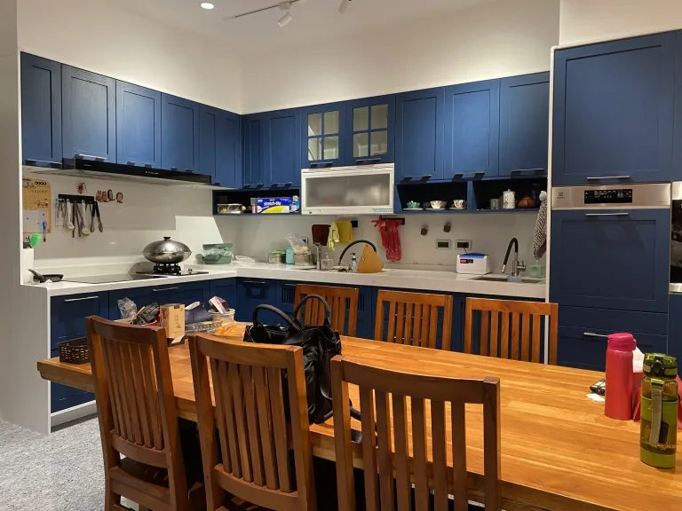 餐廚關係:從用餐區可看見廚房主要工作面與收納配置。 從餐桌方向觀看深藍色現代框型廚房